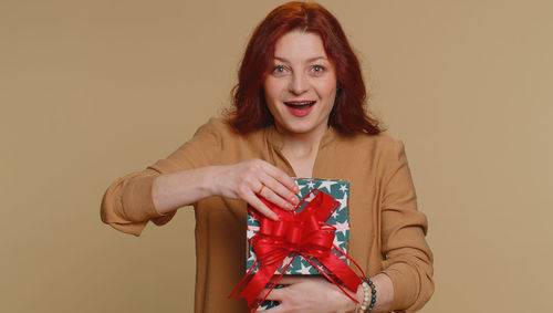 Portrait of young woman standing against yellow background