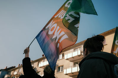 Low angle view of people holding flag against clear sky