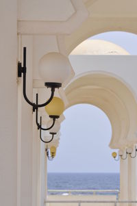 Lamp post by sea against clear sky