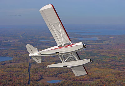 Airplane flying over land against sky