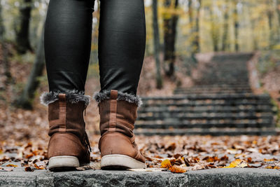 Low section of person wearing autumn leaves in forest