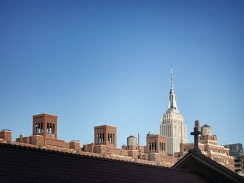 High section of church and empire state building against clear blue sky