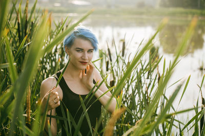 Portrait of young woman amidst cattails on field