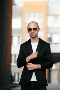 Beautiful mature bald white man in sunglasses and a fashionable jacket smiling at the camera