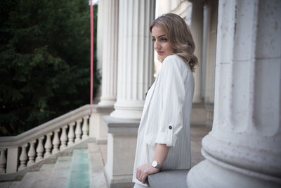 Side view of thoughtful young woman standing amidst columns on steps