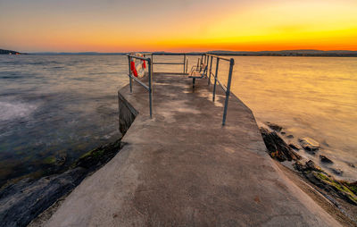 Pier amidst sea against sky during sunset