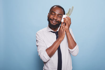 Young woman holding dentures while standing against blue background