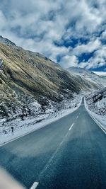 Road amidst snowcapped mountains against sky