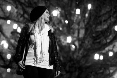 Low angle view of woman standing against illuminated tree