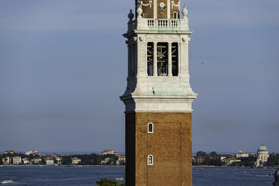 Clock tower by sea against sky in city