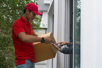 Young man delivering package to customer at doorway