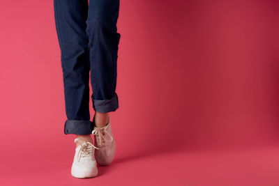 Low section of woman standing against red background