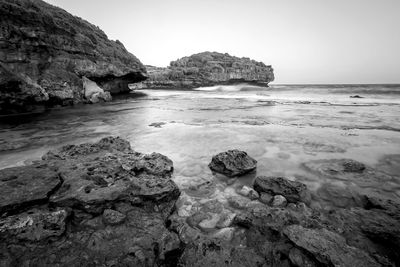 Rocks in sea against clear sky