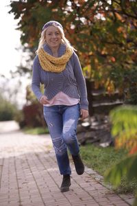 Portrait of smiling young woman standing on footpath
