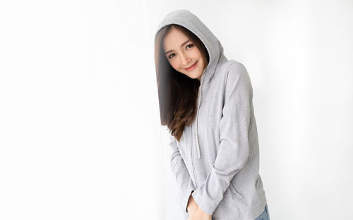 Portrait of smiling young woman standing against white background