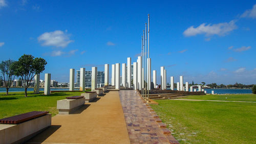 Footpath leading towards city against blue sky