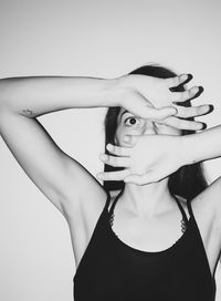 Portrait of shocked woman covering face with hands against white background