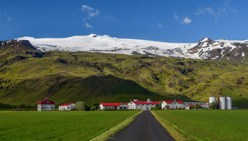 Houses on field by mountain against sky