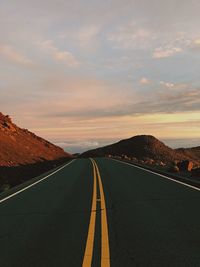 Diminishing perspective of empty road against cloudy sky during sunset