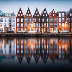 Reflection of residential buildings by river at dusk