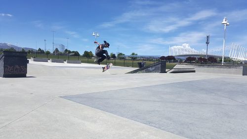 Man skateboarding on city street against sky