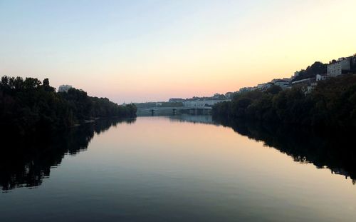 Scenic view of lake against clear sky during sunset