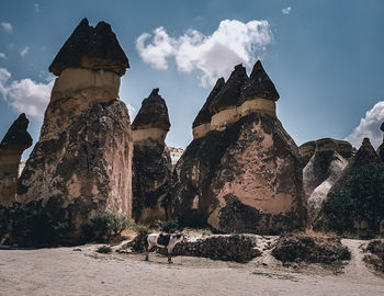 Panoramic view of rock formation amidst buildings against sky