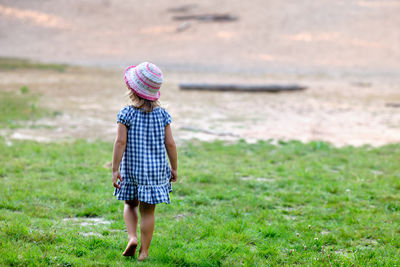 Rear view of girl walking on grass