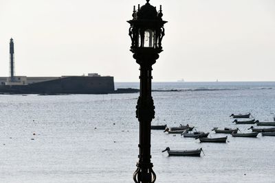 Sailboats moored on sea against clear sky
