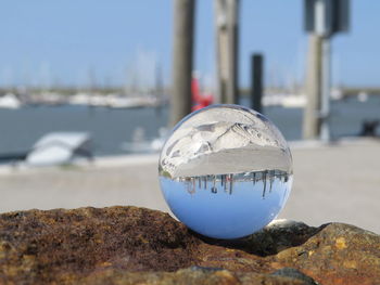 Close-up of crystal ball on beach against clear sky