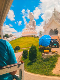 Statue against temple and building against sky