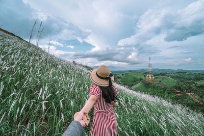 Rear view of woman holding hands while standing on field