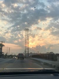 Cars on road against sky during sunset