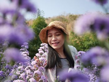 Portrait of smiling young woman against purple flowering plants