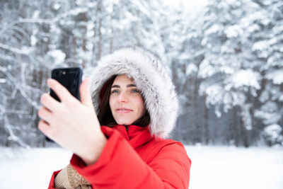 Portrait of smiling young woman standing on snow