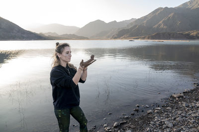 Woman putting mud on hands and face while enjoying outdoors in nature.