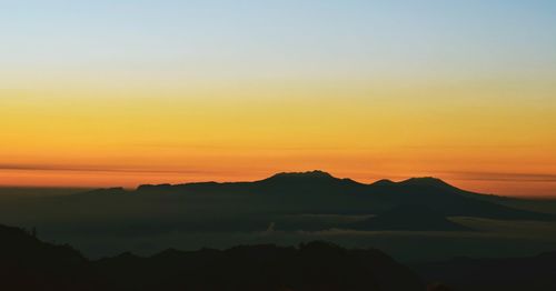 Scenic view of silhouette mountains against romantic sky at sunset