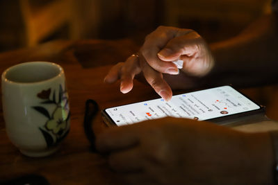 Midsection of man holding smart phone on table