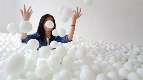 Full length of woman sitting on white balloons