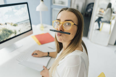 Portrait of funny young woman at desk pouting mouth