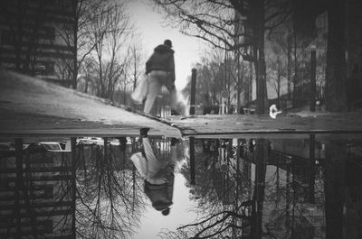 Rear view of man walking by bare trees