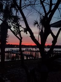 Silhouette tree by river against sky during sunset