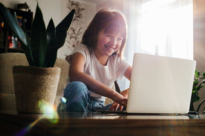 Girl schoolgirl sits at home in front of a laptop and smiles. concept of home, online