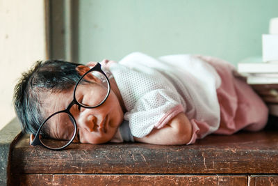 Close-up of baby girl wearing eyeglasses while lying on table