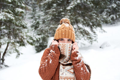 Portrait of man wearing hat against snow covered tree