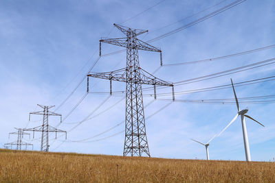 Electricity pylon on field against sky