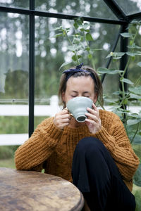 Woman having coffee in greenhouse