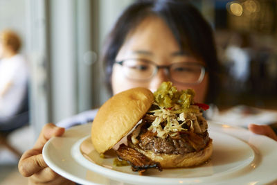 Woman showing hamburger on white plate