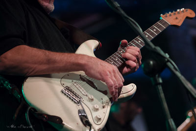 Midsection of man playing guitar