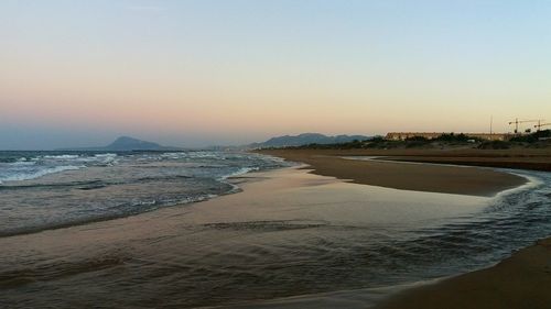 Scenic view of beach against clear sky during sunset